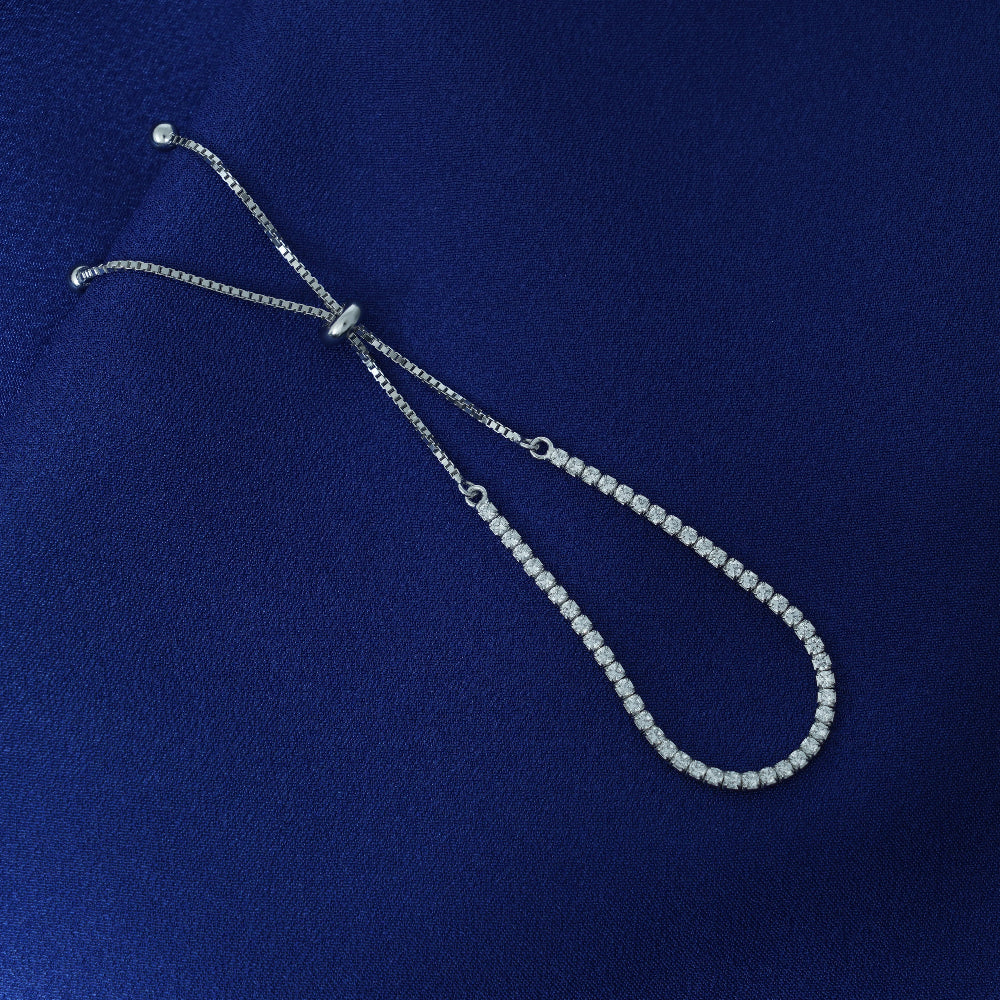 Silver tennis bracelet on a blue fabric background