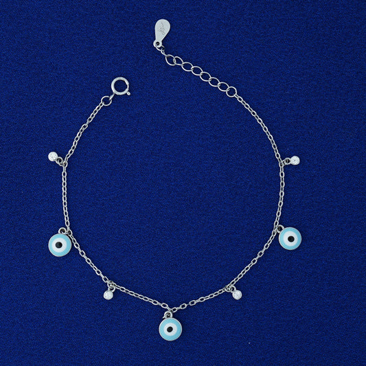 Silver bracelet with blue evil eye charms on a blue background