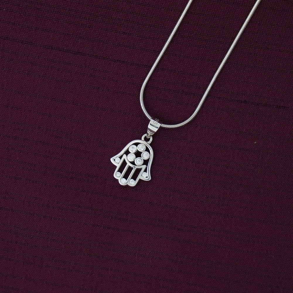 Silver Hamsa hand pendant necklace on a dark purple fabric background