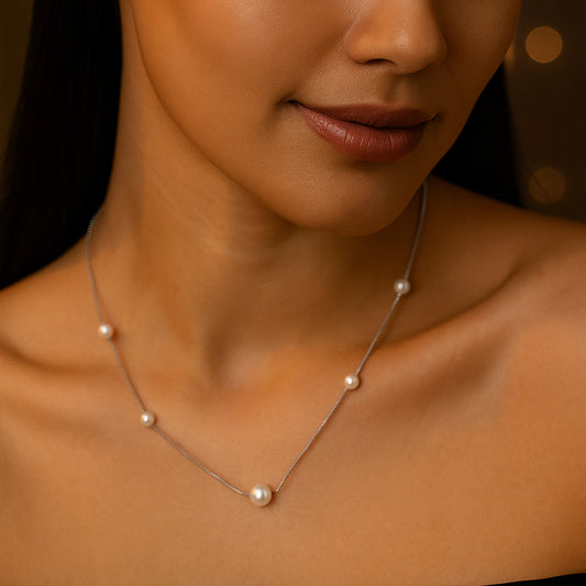 Pearl necklace on a model with a warm, brown background