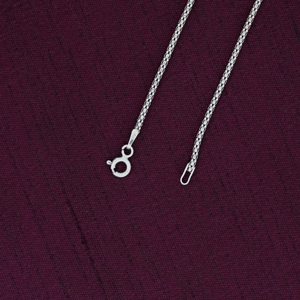 Silver crub chain necklace on a purple fabric background