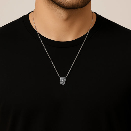 Silver necklace with a pendant on a person wearing a black shirt against a beige background