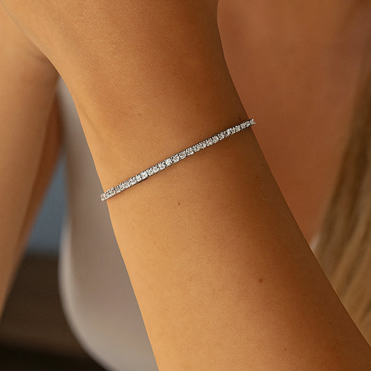 Silver tennis bracelet on a person's wrist with a blurred background