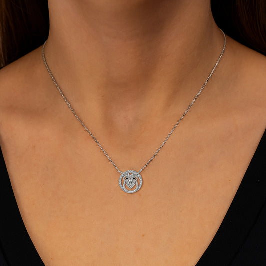 Silver owl pendant necklace on a person wearing a black top.