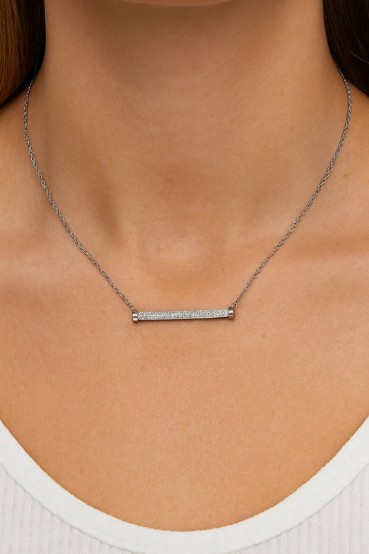 Silver bar necklace on a person wearing a white top