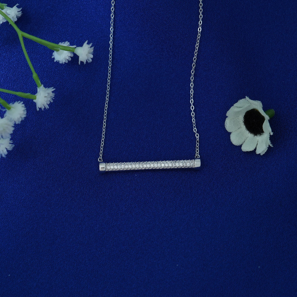 Silver necklace with a bar pendant on a blue background with white flowers