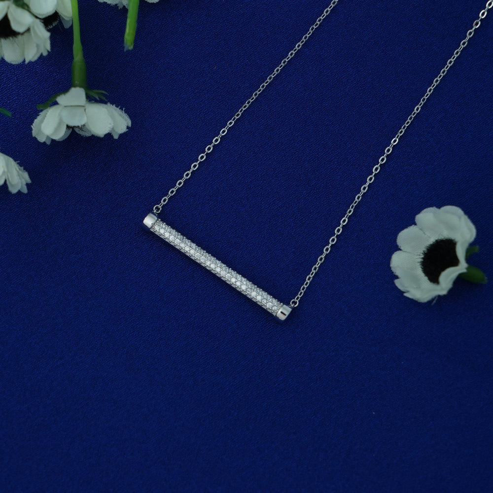 Silver necklace with a bar pendant on a blue background with white flowers