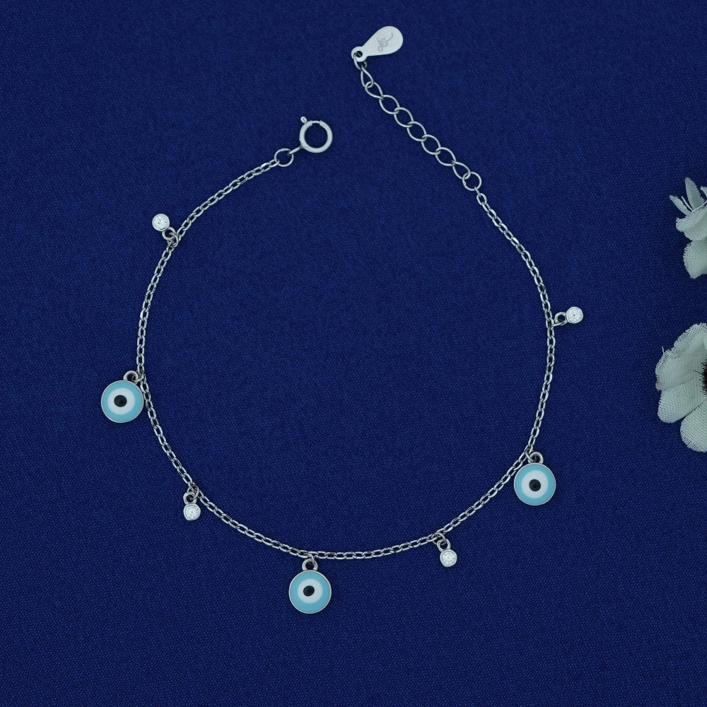 Silver anklet with blue evil eye charms on a dark blue background