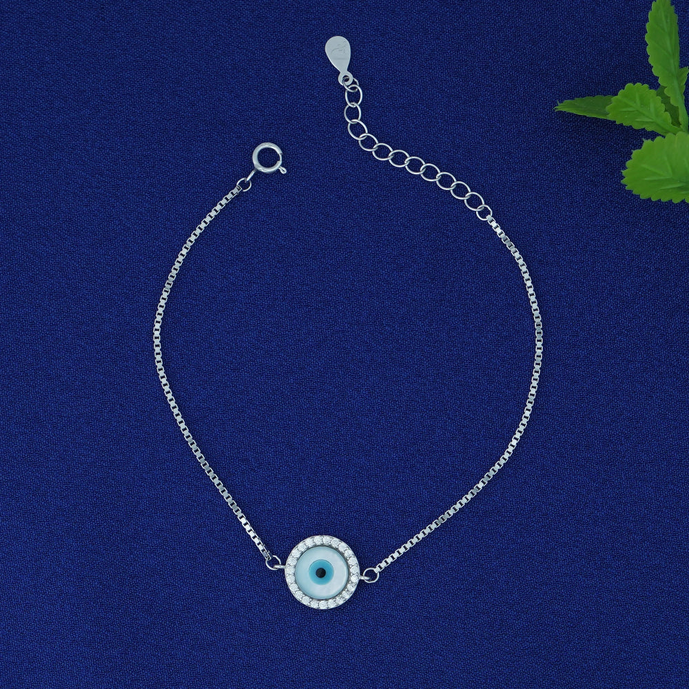 Silver bracelet with a blue evil eye charm on a blue background