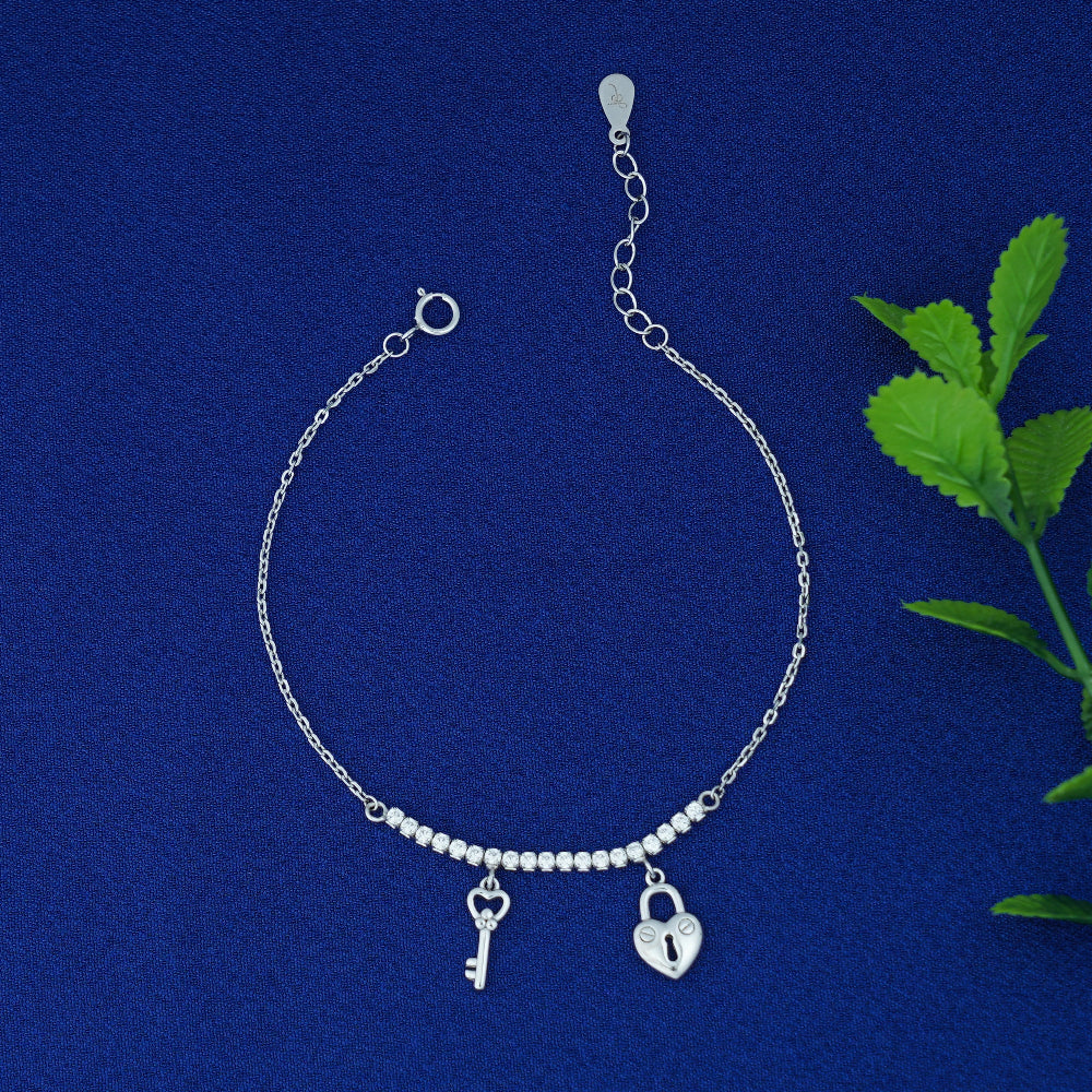 Silver bracelet with key and lock charms on a blue background