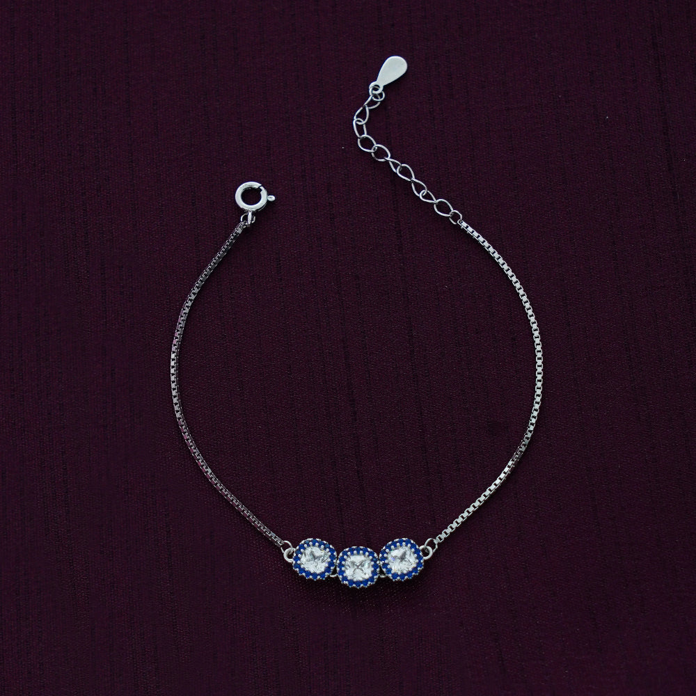 Silver bracelet with three blue stones on a dark purple background